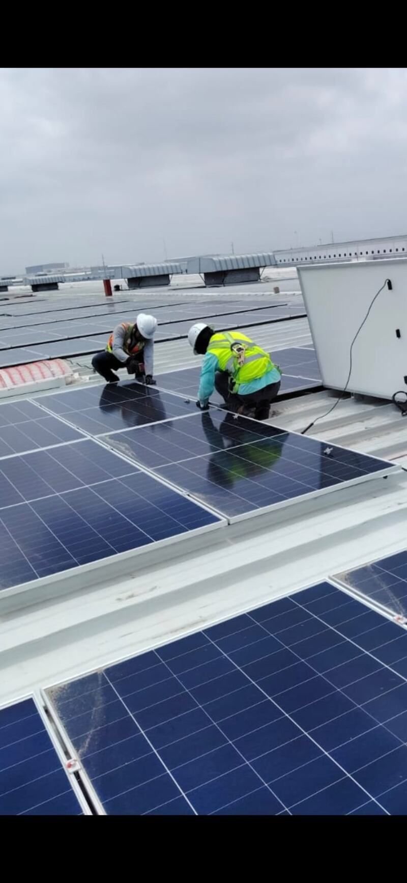 Técnicos instalando paneles solares con equipo de seguridad